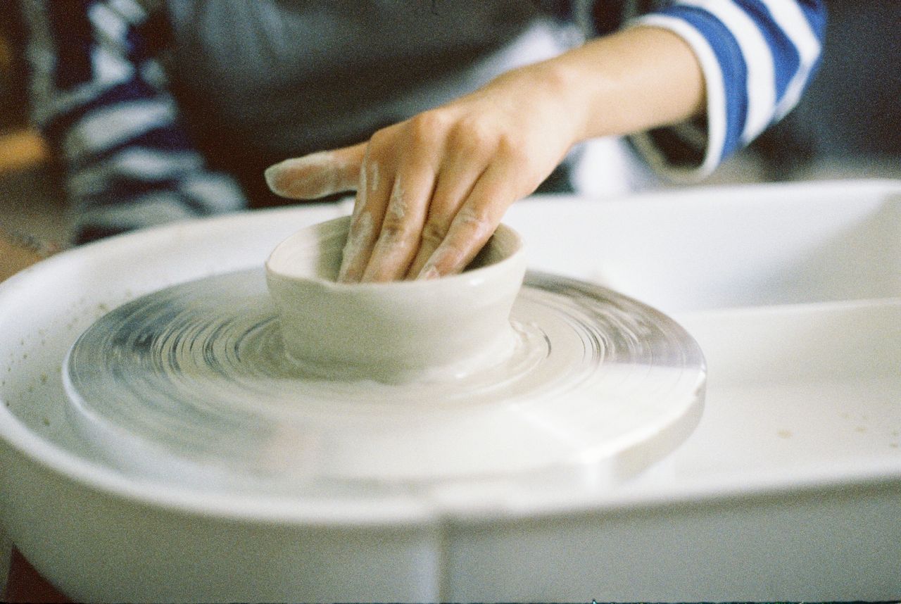 Close-up of hands shaping clay on a pottery wheel, showcasing the art of handmade ceramics.